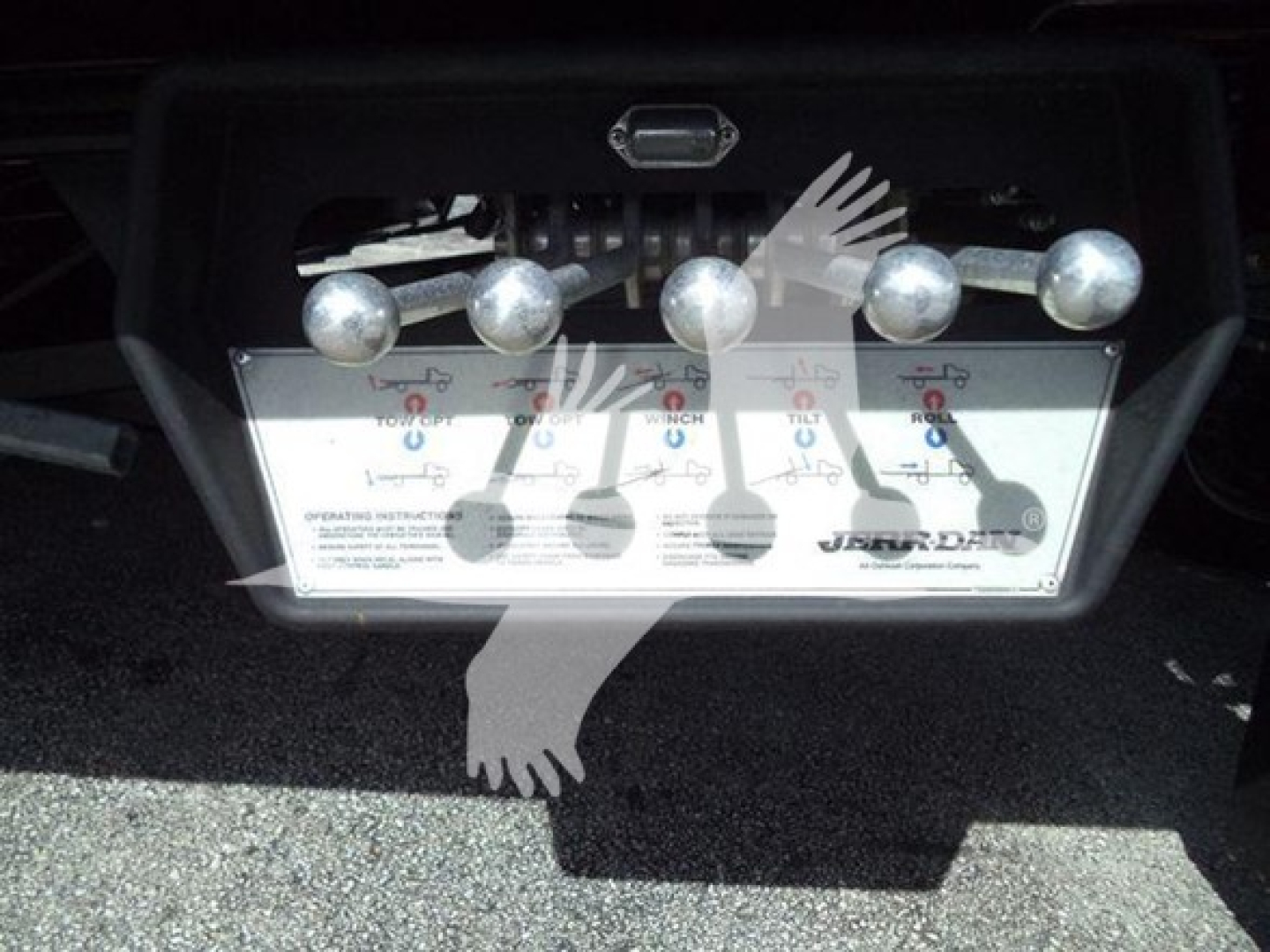 Trailer hitch/bed area showing control panel with multiple round knobs labeled and a white instruction placard.