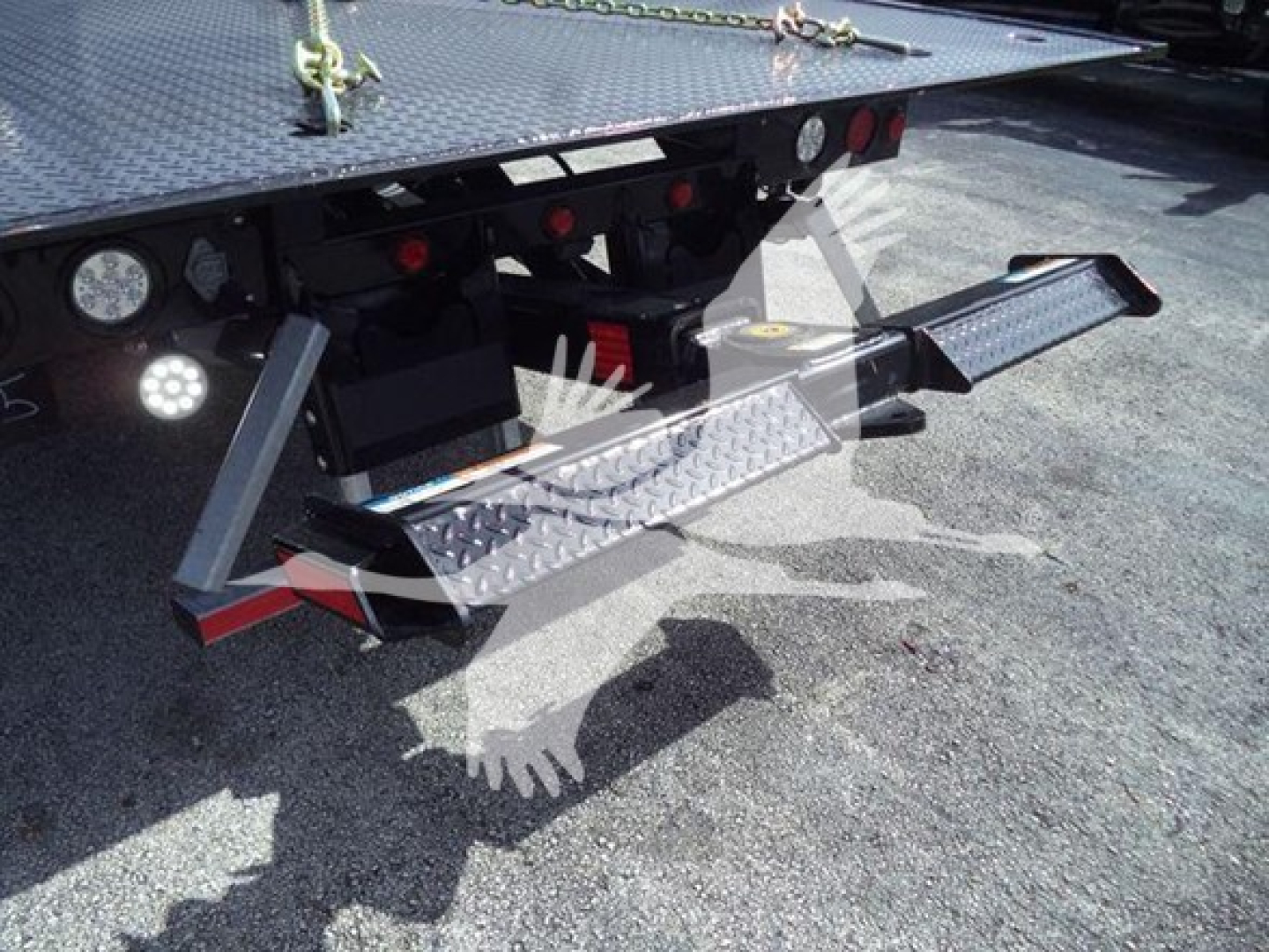 Truck rollback equipment rear view showing heavy-duty bumper steps and platform with textured metal surface and safety chains.