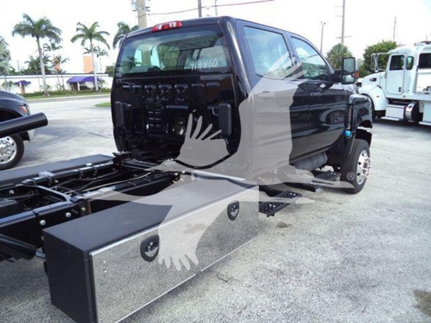 Truck cab with chassis and hookups showing side view and flatbed base under dealer lot lighting.