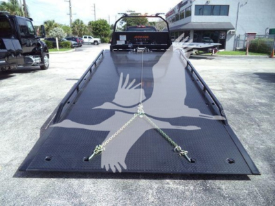 Tow truck flatbed with loading ramp, chain ties, and hydraulic controls visible from rear, 2023 International CV unspecified.
