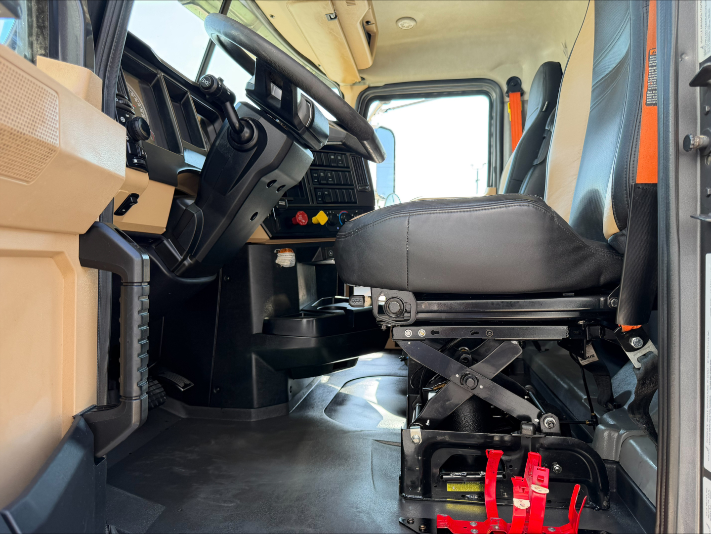 Cab interior of a 2023 Mack GR64F dump truck showing driver seat, dashboard, and controls with beige and black trim.