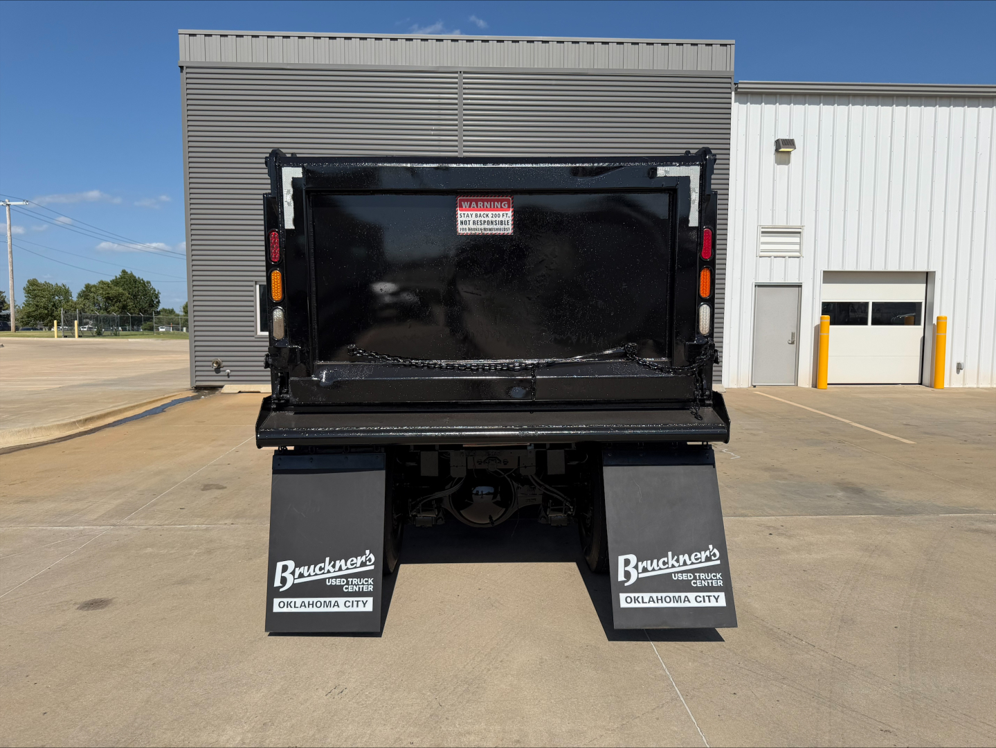 Truck dump bed rear view with black tailgate and mud flaps reading Bracken’s OKLAHOMA CITY