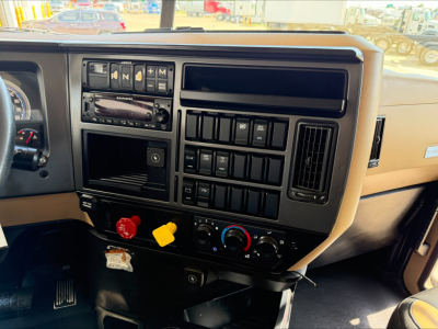 Dashboard and center console of a 2023 Mack GR64F dump truck showing controls, switches, and knobs.