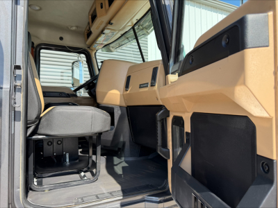 Cab interior of a 2023 Mack GR64F dump truck showing tan dashboard, steering wheel, and seating area.