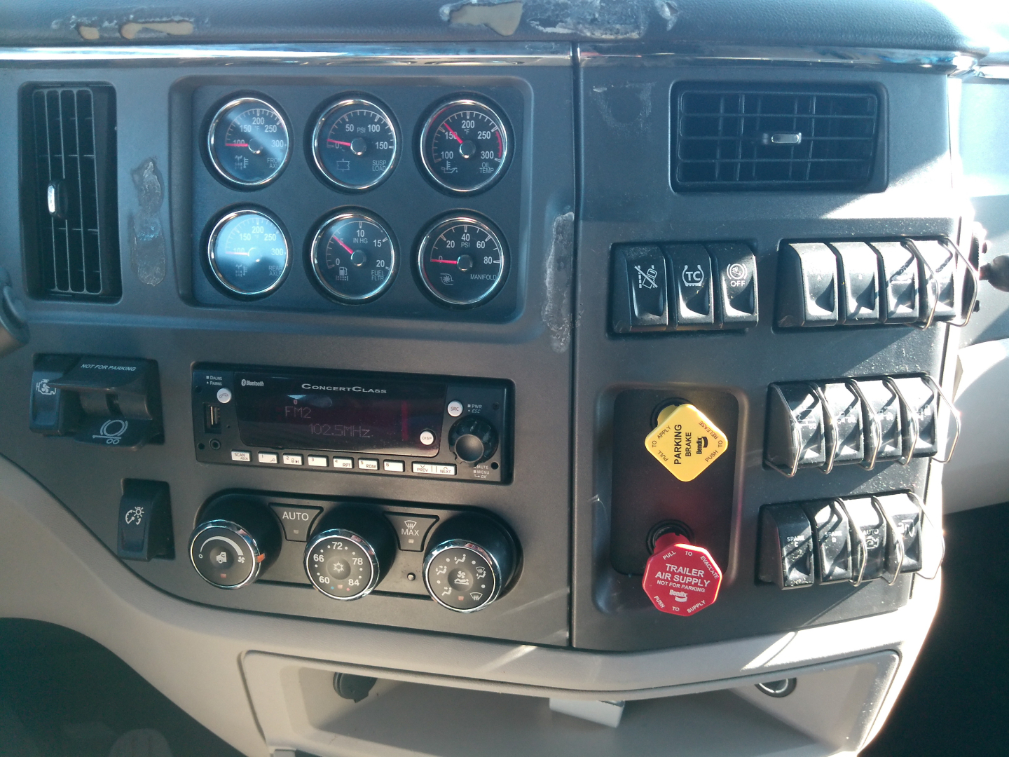 Truck dash panel with multiple gauges, switches, and control knobs; Peterbilt 579 interior cluster visible.