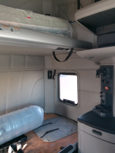 Peterbilt 579 sleeper cab interior showing bunk area and side cabinet with window.