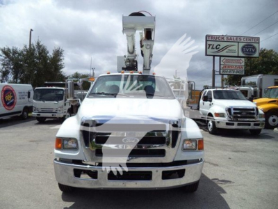 Versalift VST40i crane truck front view with mounted bucket lift, dealership lot in background. Visible text includes company signs and plate area; no legible model numbers or specs besides the truck front.