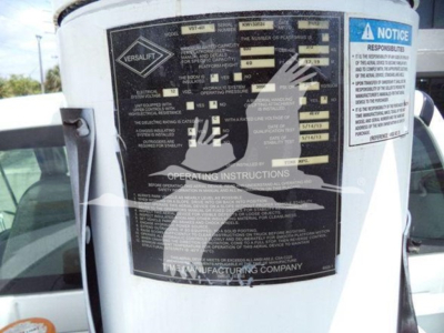 Versalift VST40i crane operating instructions label on white equipment; various specifications and warning panels, VIN and stock number nearby partially visible.