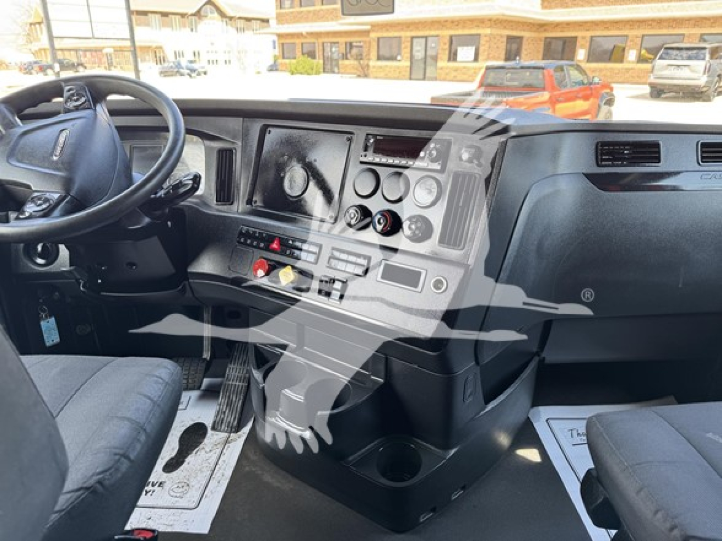 Dashboard of a Freightliner Cascadia truck cab with steering wheel and control panel; visible text includes various gauges and switches on the central console.