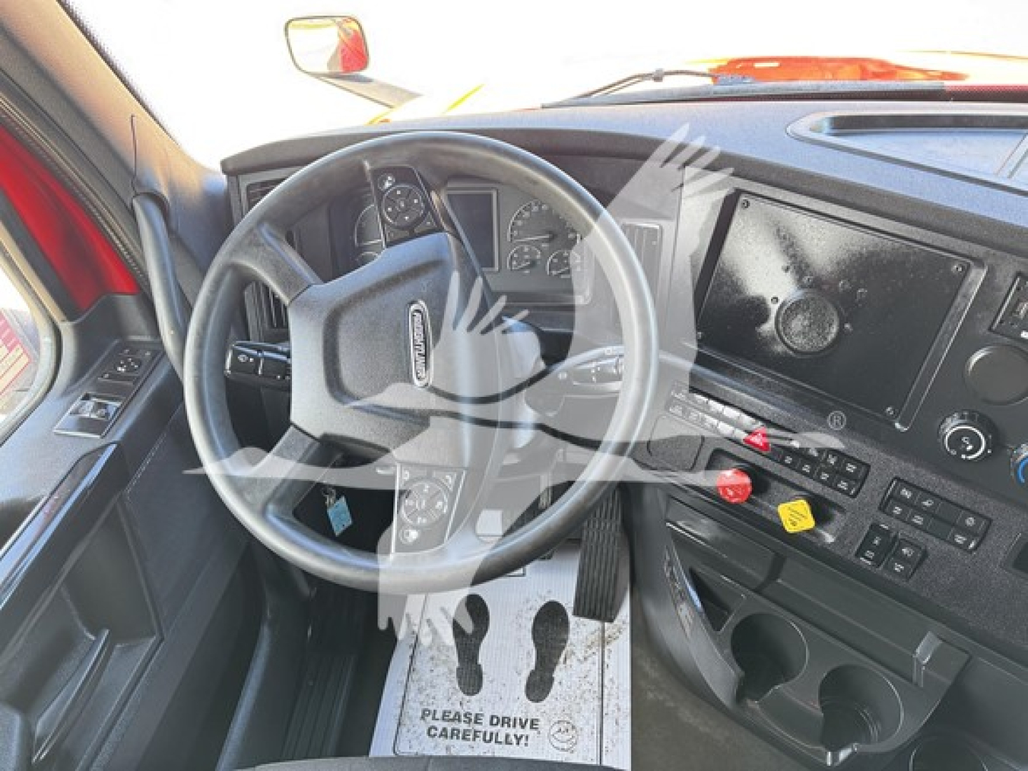 Truck cab interior showing steering wheel and dashboard with gauges and controls in a Freightliner Cascadia.