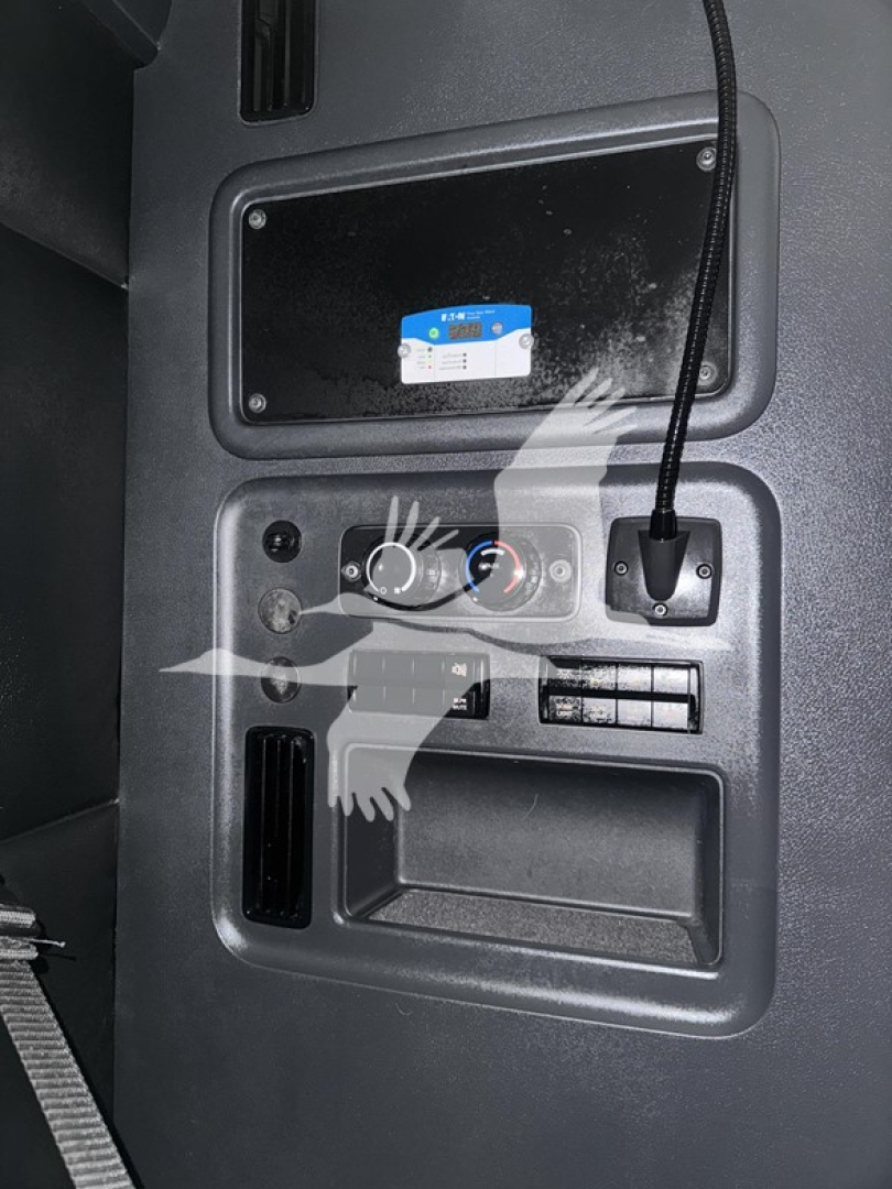 Truck dashboard panel with controls and a small screen, 12V power outlet, and a blue sticker on a black surface; no identifiable logos visible.