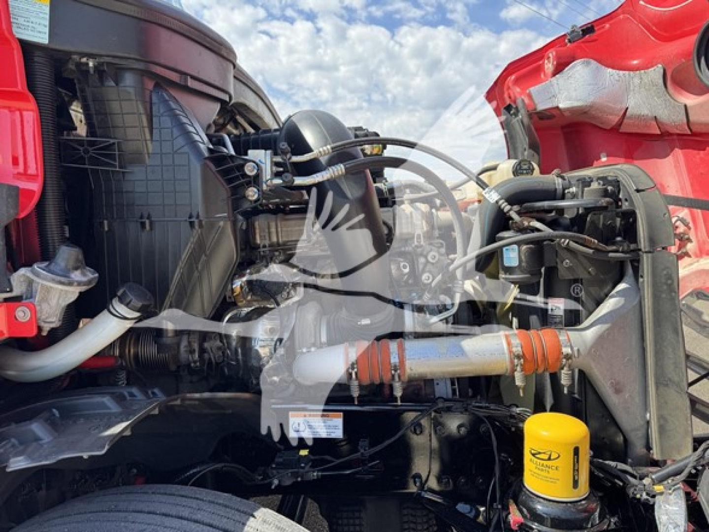 Truck engine bay of a 2023 Freightliner Cascadia showing component labels, hoses, and a yellow SENTRY DEF reservoir cap.