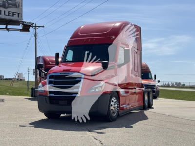 2023 Freightliner Cascadia 126 semi-truck front view with red cab and sleeper, side view mirrors, and windshield glare.