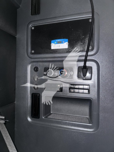 Truck dashboard panel with controls and a small screen, 12V power outlet, and a blue sticker on a black surface; no identifiable logos visible.
