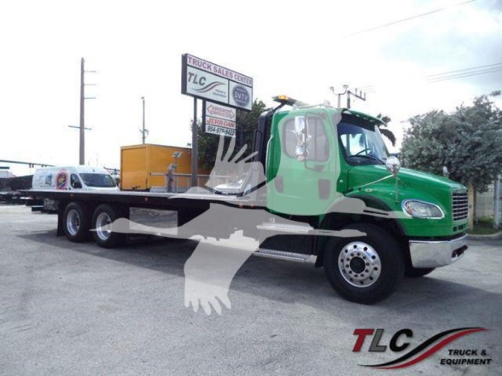 Truck body showing Freightliner M2-106 rollback with green cab and yellow tool box, dealer sign in background. Clear text on signs and stickers.