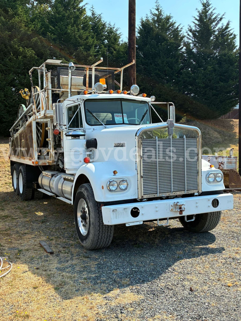 Kenworth W900A truck in-service showing front grille and chrome bumper with utility bed and ladder rack.