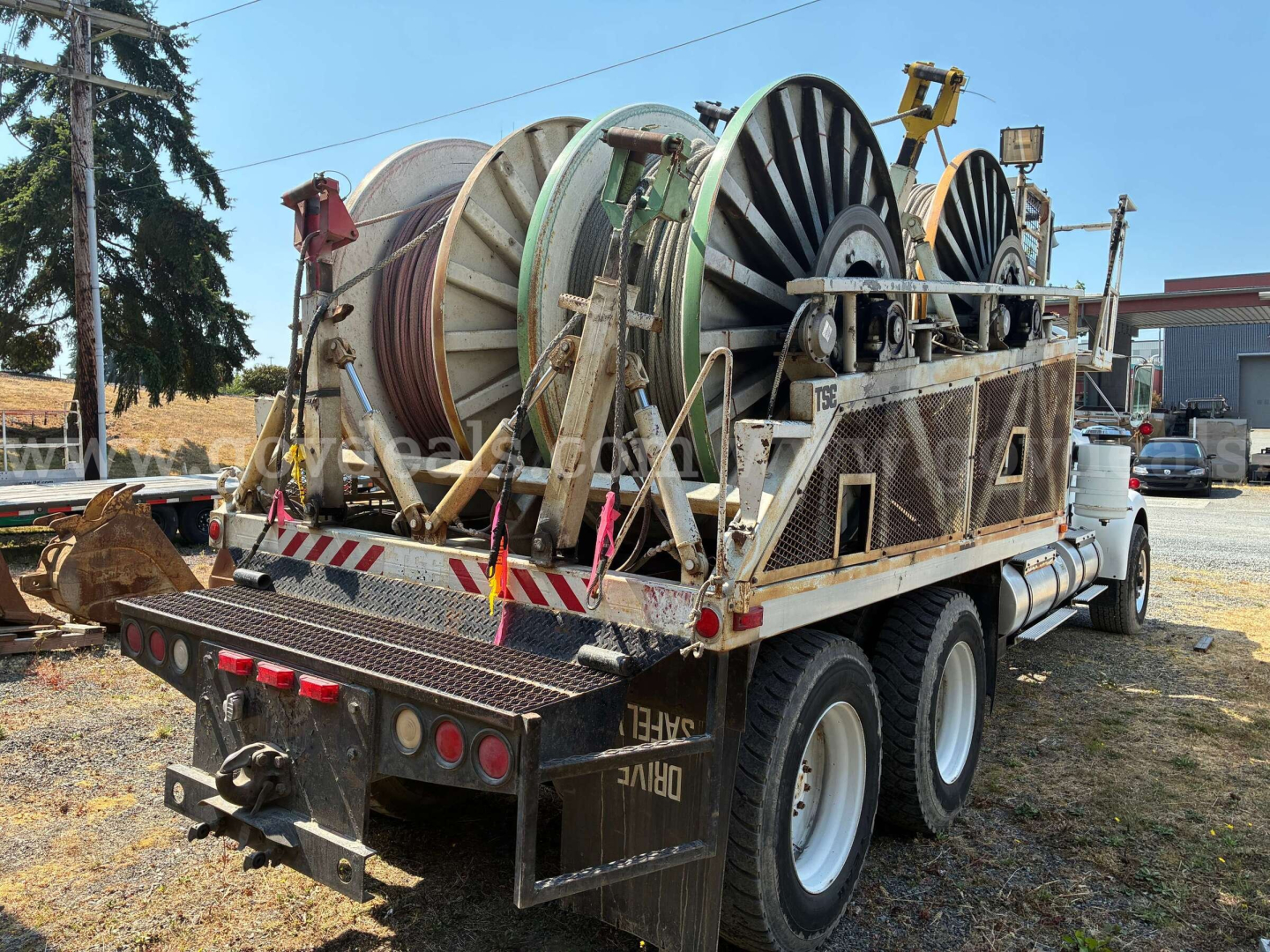 Kenworth W900A service/utility truck with large reel cables mounted on a flatbed, rear view showing dual rear wheels and equipment