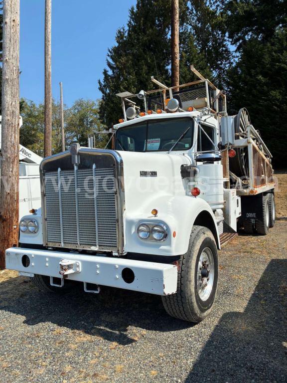 Kenworth W900A concrete mixer truck in white, front view showing large grille, round headlights, bumper, and mixer drum equipment on the chassis.