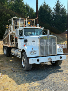 Kenworth W900A truck in-service showing front grille and chrome bumper with utility bed and ladder rack.