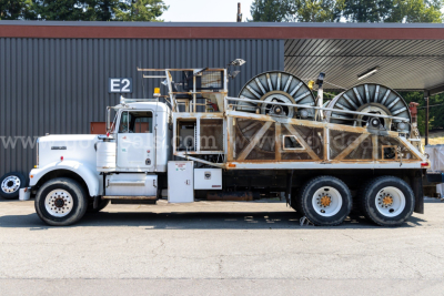 Kenworth W900A dump-style truck side view with large spool winders on flatbed and steel framework.
