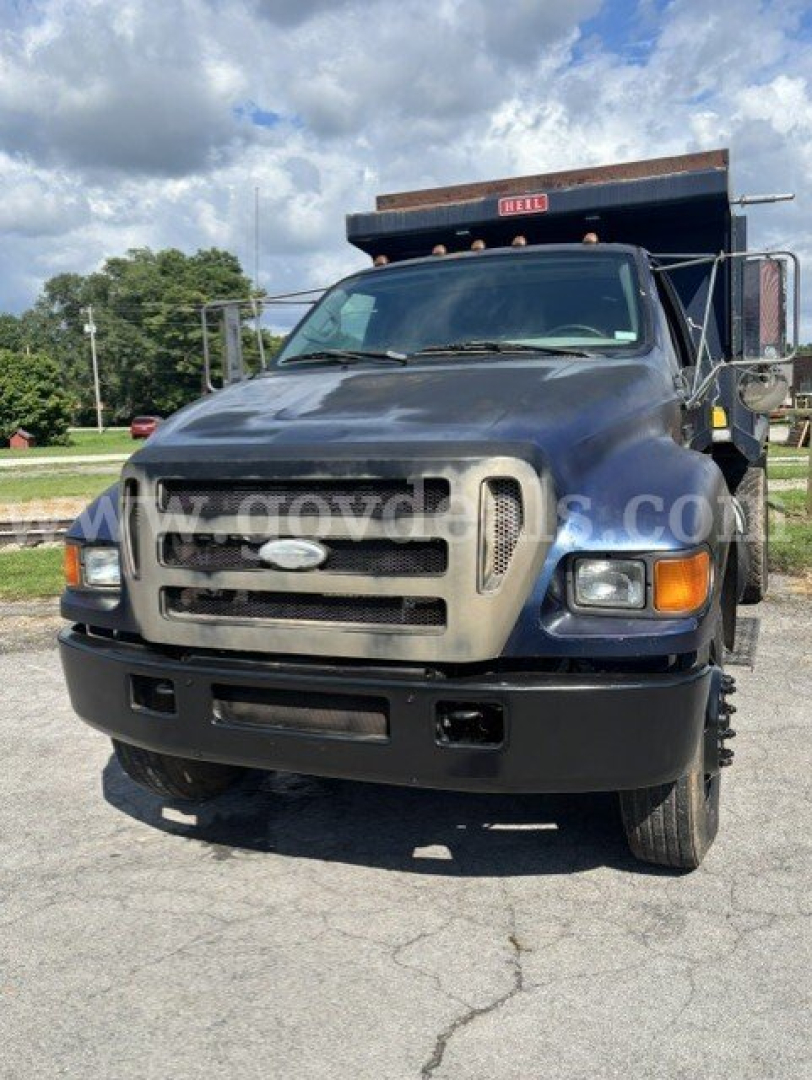Ford F-750 dump truck front view showing blue cab, large gray grille, and black bumper.