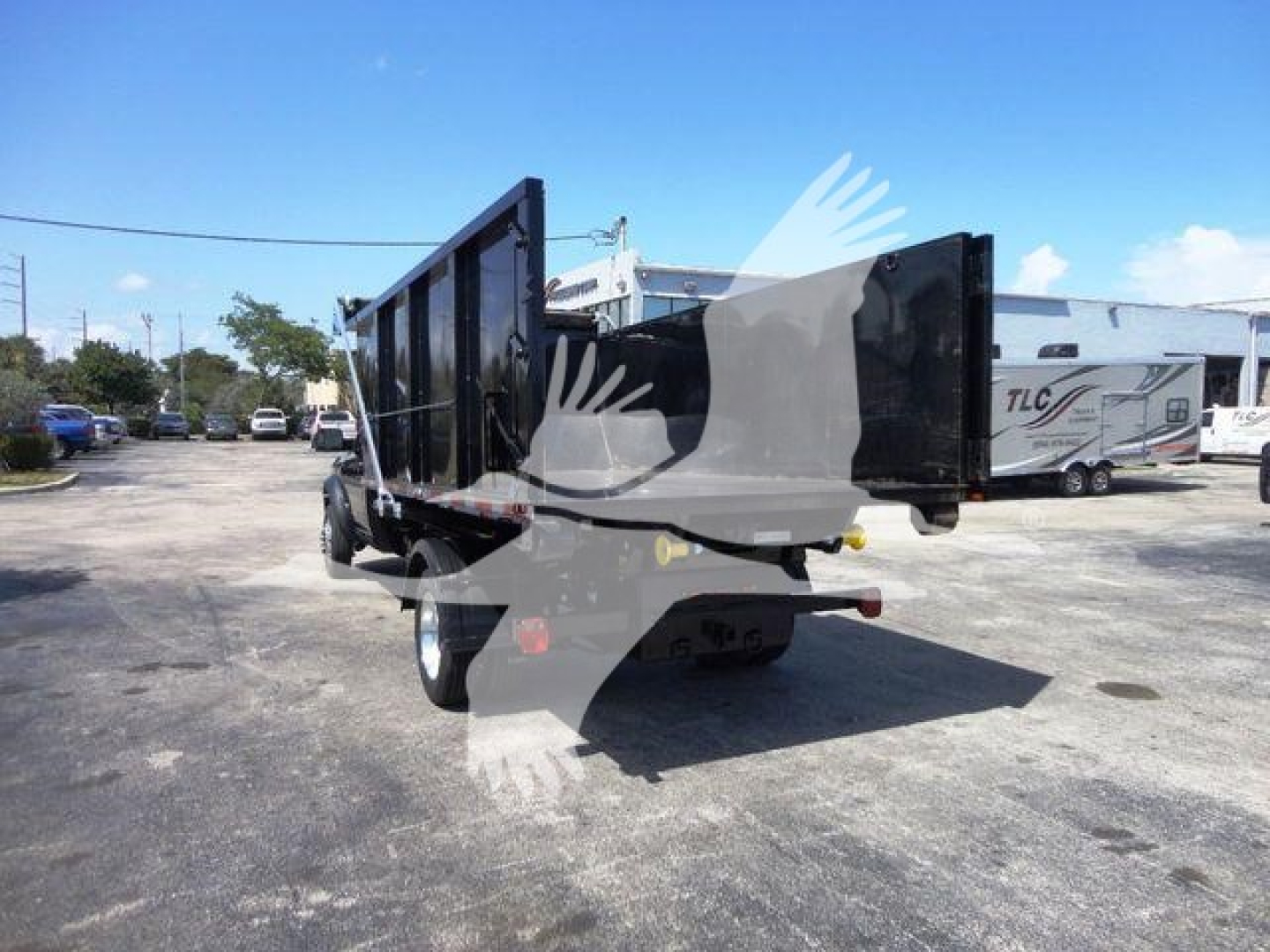 Ram 5500 dump bed truck rear view showing dump body and taillights with a parking lot background.