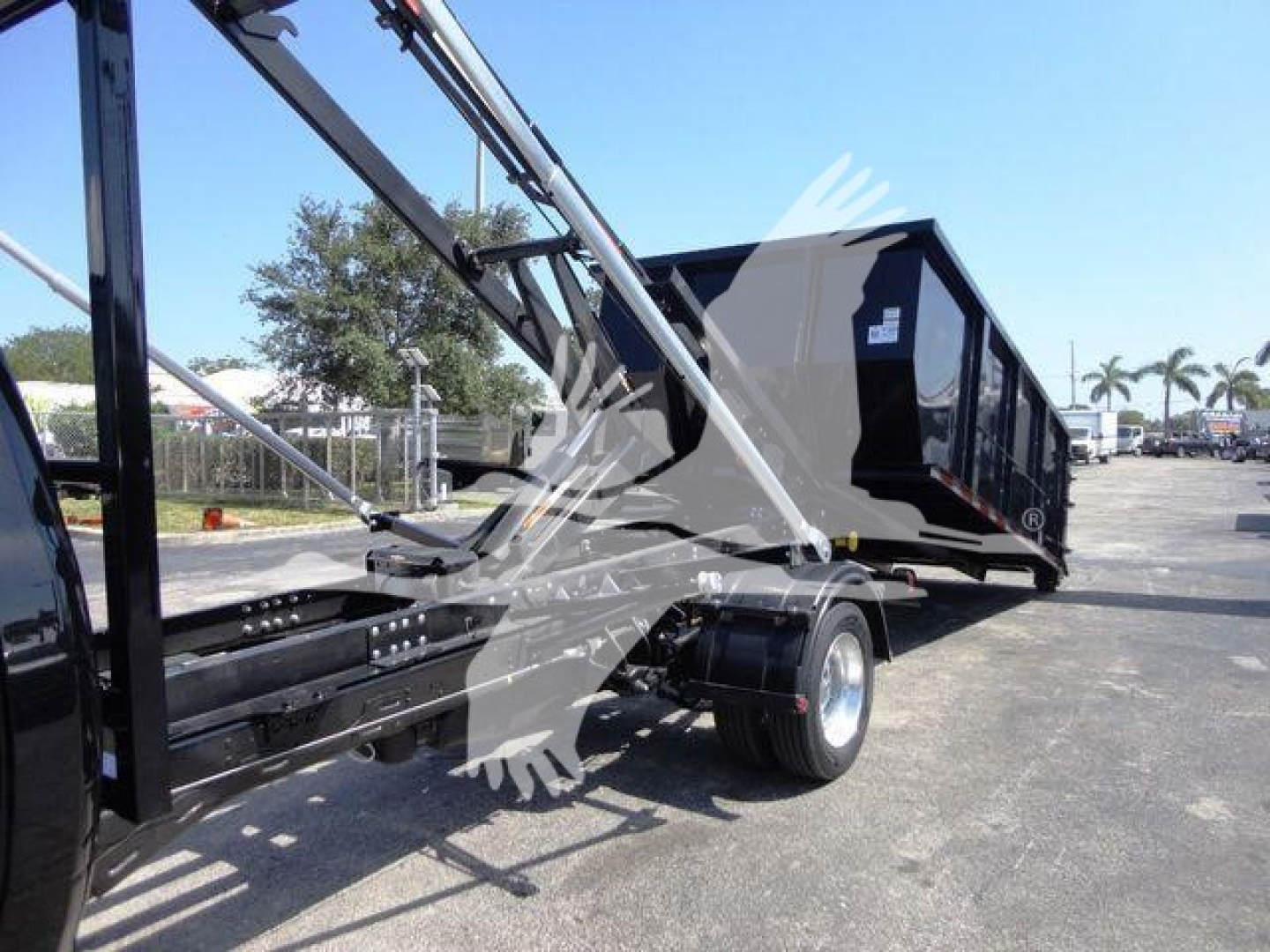 Ram 5500 HD roll-off truck with dumping container and hydraulic arm in side view showing chassis and rear wheel.