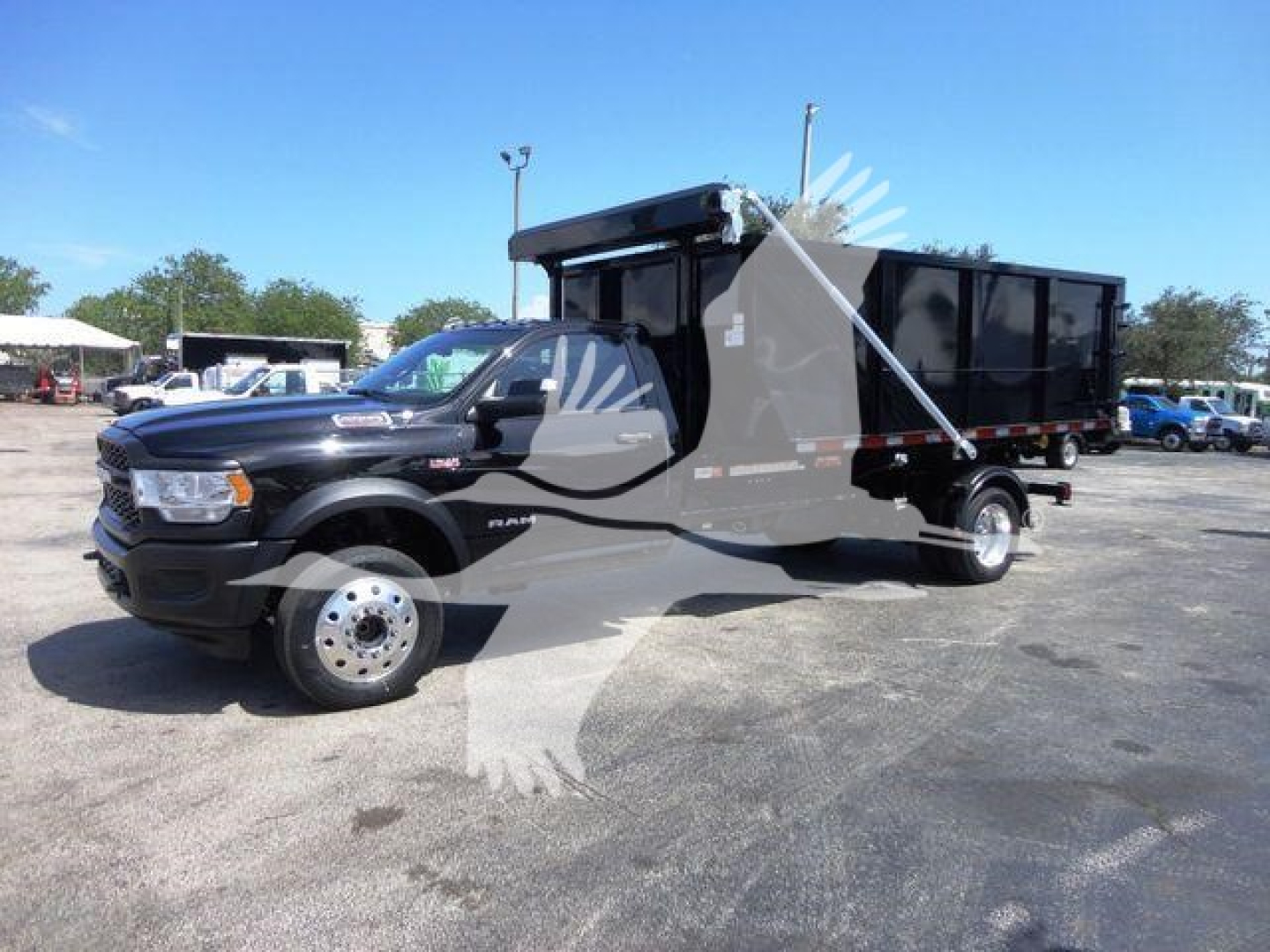 Ram 5500 heavy-duty roll-off truck in black with large open-top dump bed and dual rear wheels, front grille and headlamps visible.