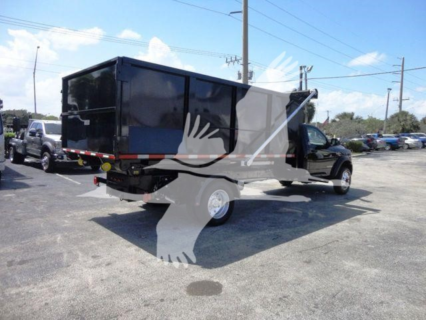 Ram 5500HD roll-off truck with a black enclosed cargo box, rear view shows dual rear tires, hitch, and taillights. Overlay watermark of a bird in flight across the image.