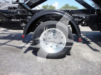 Truck wheel and suspension view showing single rear axle, heavy-duty frame, and aluminum lugged wheel on a Ram 5500 roll-off truck.