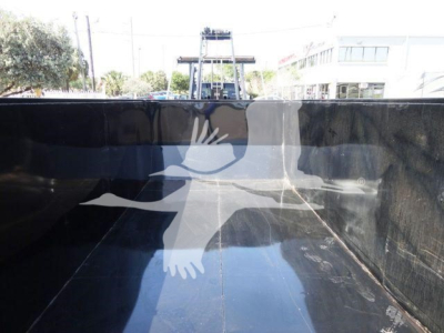 Ram 5500 truck bed interior showing flatbed/rolloff cargo area with clean black painted surfaces and reflections.