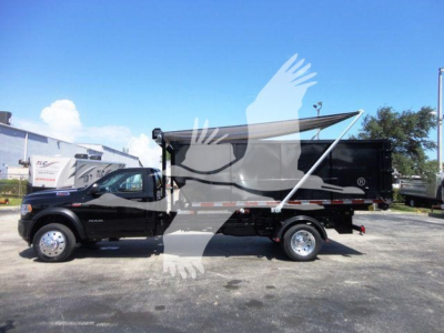Ram 5500 dual rear wheel truck with a roll-off dump body, black color, side view showing cargo bed and tarp cover.