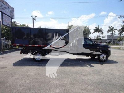 Ram 5500 HD roll-off truck side view showing cab and long black bed with white front bumper and wheel wells.