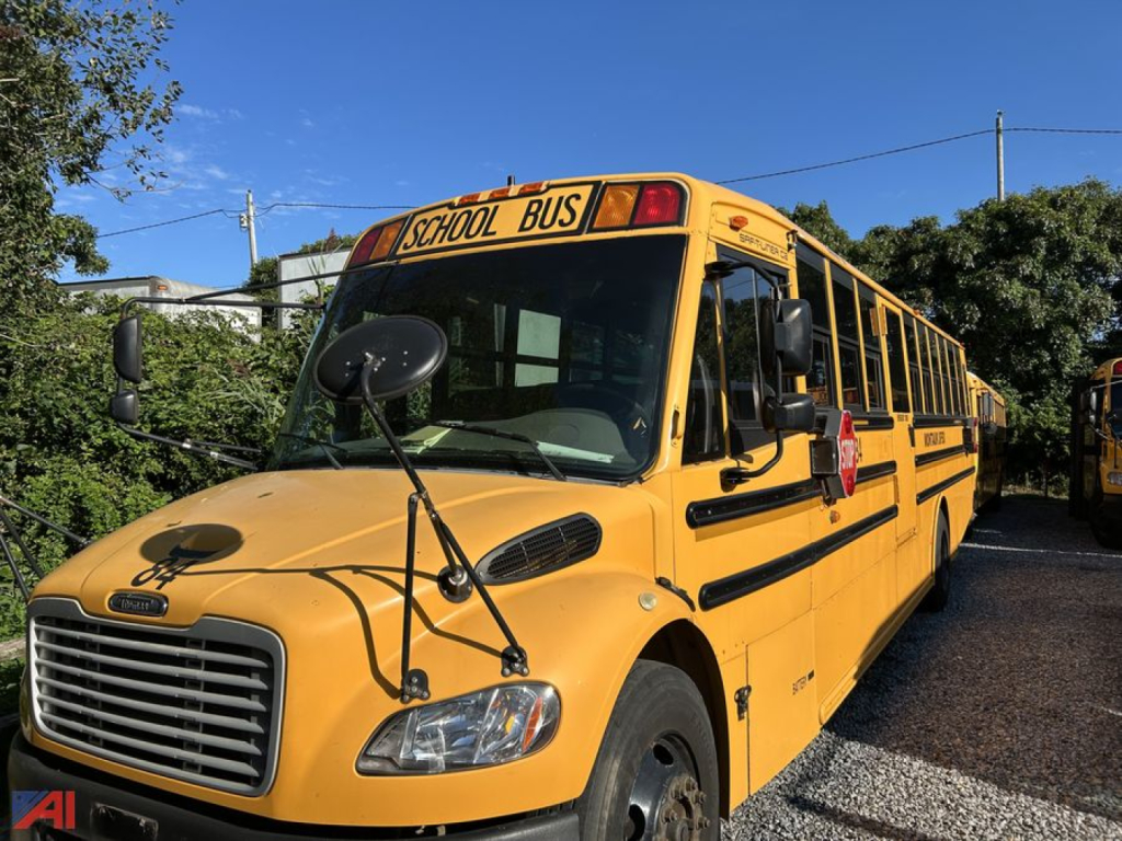 School bus showing front-left side view with 'SCHOOL BUS' sign on top, yellow Freightliner chassis, black grille, mirrors, and passenger windows.