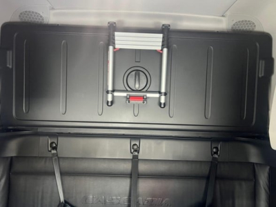 Storage box and strap hooks inside Freightliner Cascadia cabin area showing overhead hatch and secure latching mechanism.