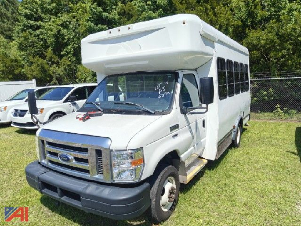 Ford E-Series cutaway shuttle bus front-left view showing passenger windows and wheelchair bus body, white exterior, bus headlights, and side steps.