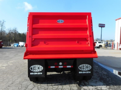 Dump truck bed of a new Western Star 47X with TEBCO branding on mud flaps and rear view showing tailgate and red cargo bed.