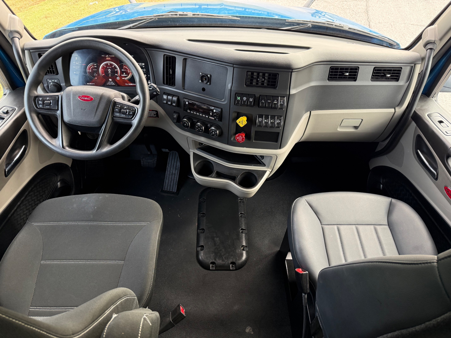 Interior cab view of a 2025 Peterbilt 579 with steering wheel, dashboard gauges, and center console labeling visible.
