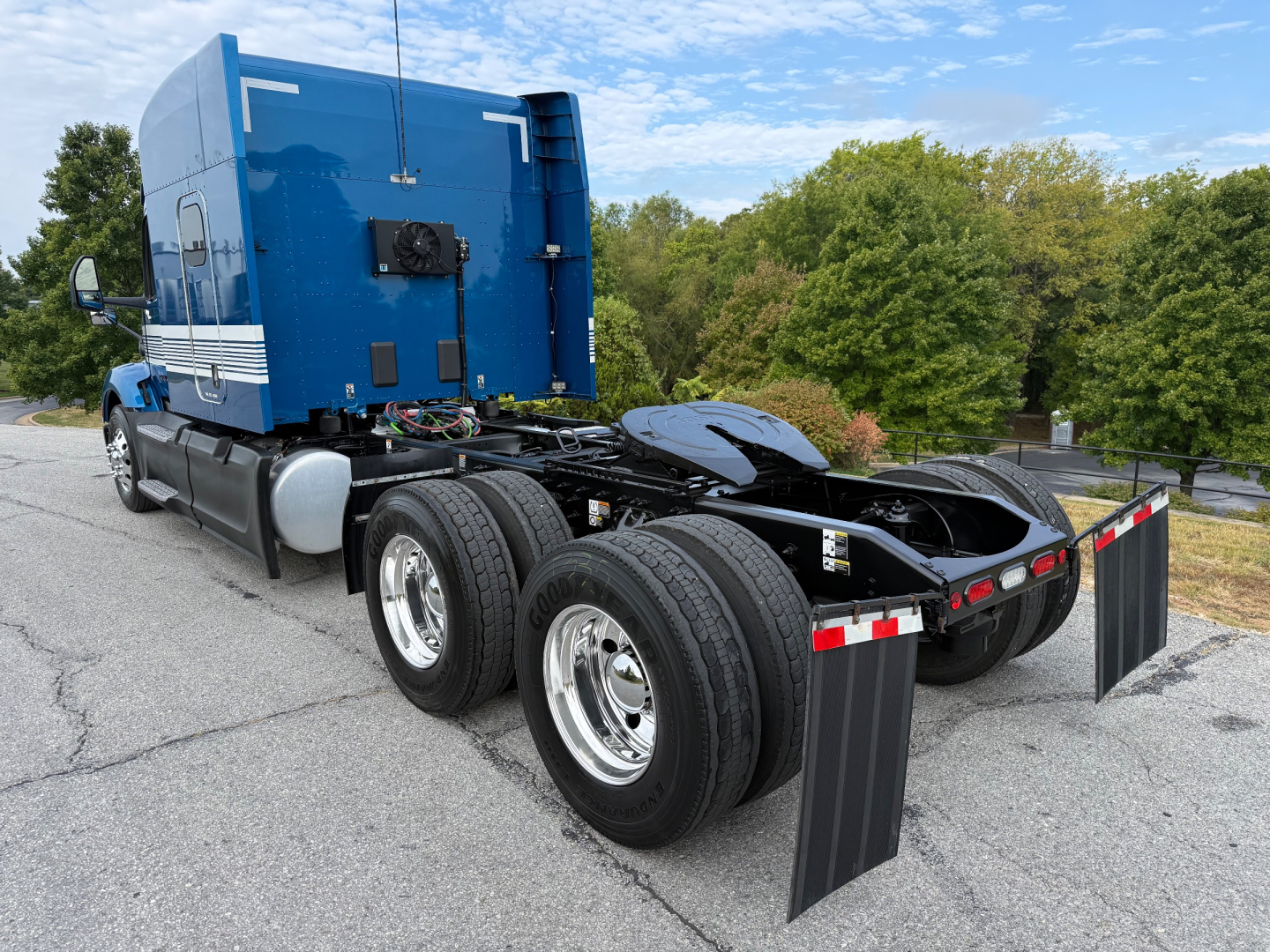 Peterbilt 579 semi truck cab and chassis with dual rear axles and mud flaps, blue sleeper cab, visible VIN plate area, in lot.