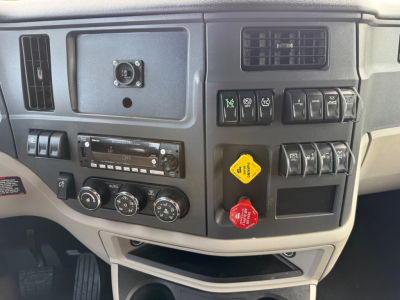 Truck dashboard interior showing control switches, storage cubby, and climate dials in Peterbilt cab.