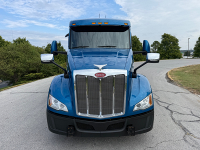 Peterbilt 579 conventional sleeper truck front view showing chrome grille and blue cab with large mirrors.