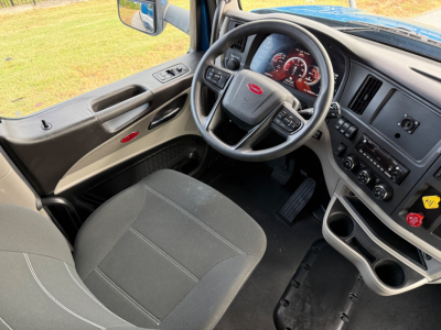 Peterbilt truck interior dashboard and steering wheel with black seats; visible controls and gauges in the dash.