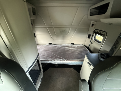 Peterbilt 579 sleeper cab interior showing bed with plastic cover and side compartments.