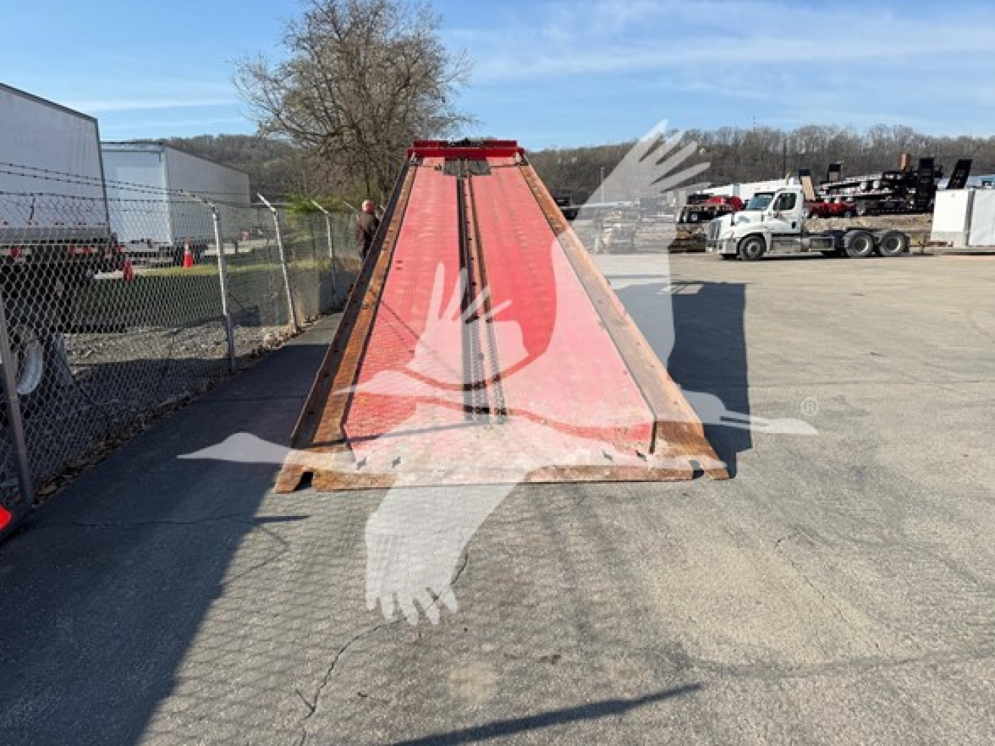 Landoll 343B trailer in a parking lot with red ramp in center, surrounding equipment and trucks in background.