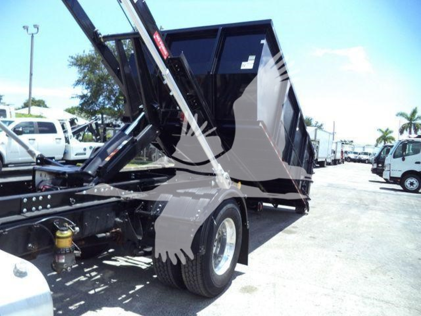 Truck chassis and dump bed of a 2020 International MV roll-off showing hydraulic mechanism and wheel.