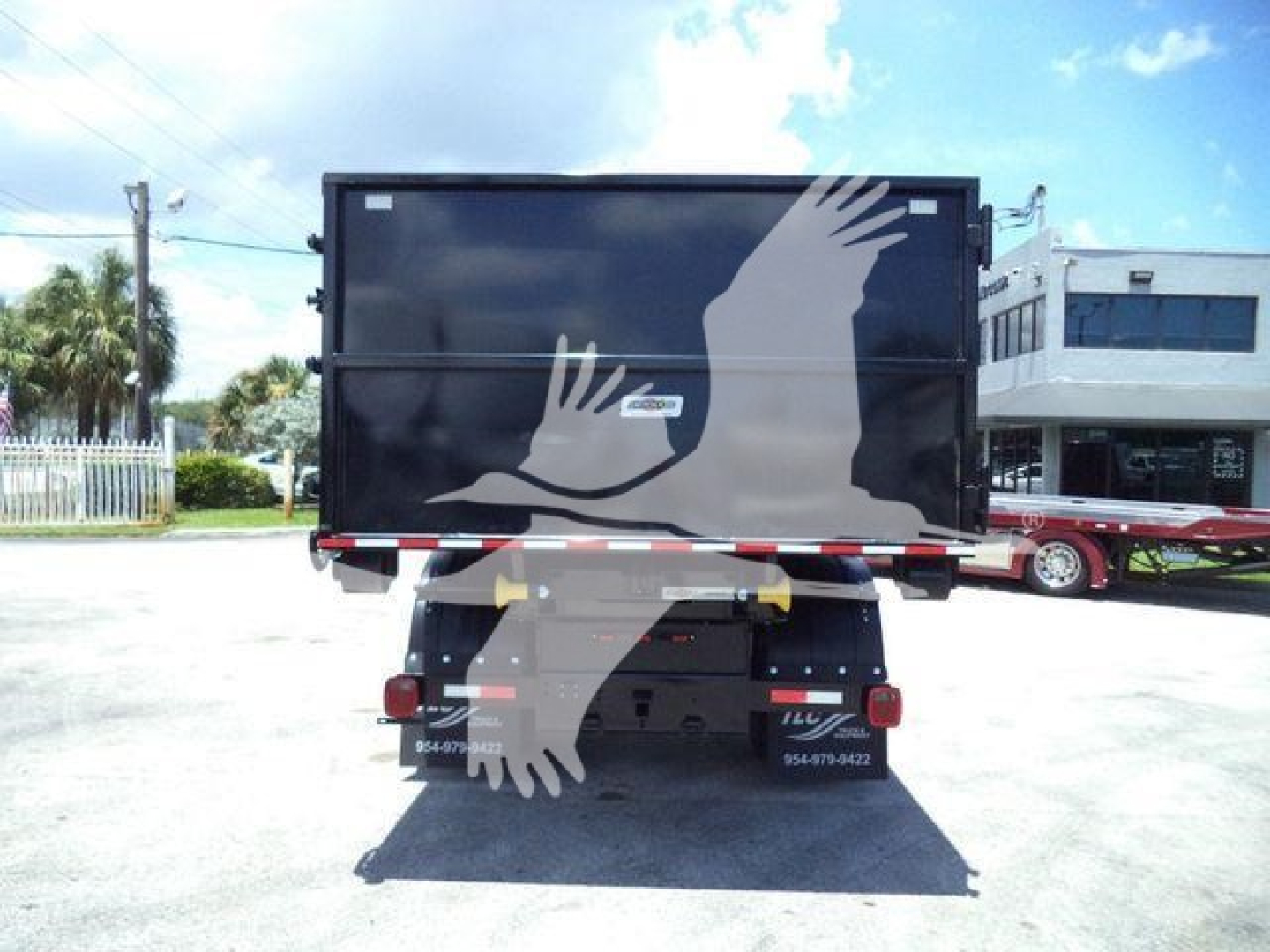 Rear view of a 2020 International MV roll-off truck with a black cargo container and white graphic of hands; license plate area and stock decals visible.
