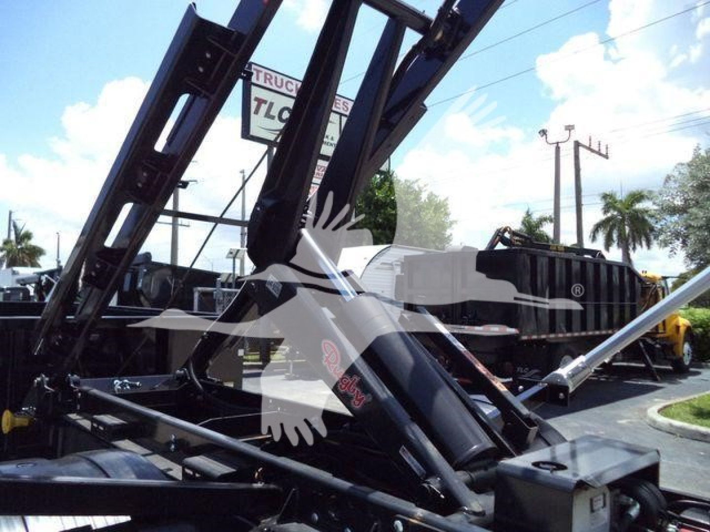 Loader crane arms and hydraulic components of a roll-off truck with hydraulic cylinders and frame in view.