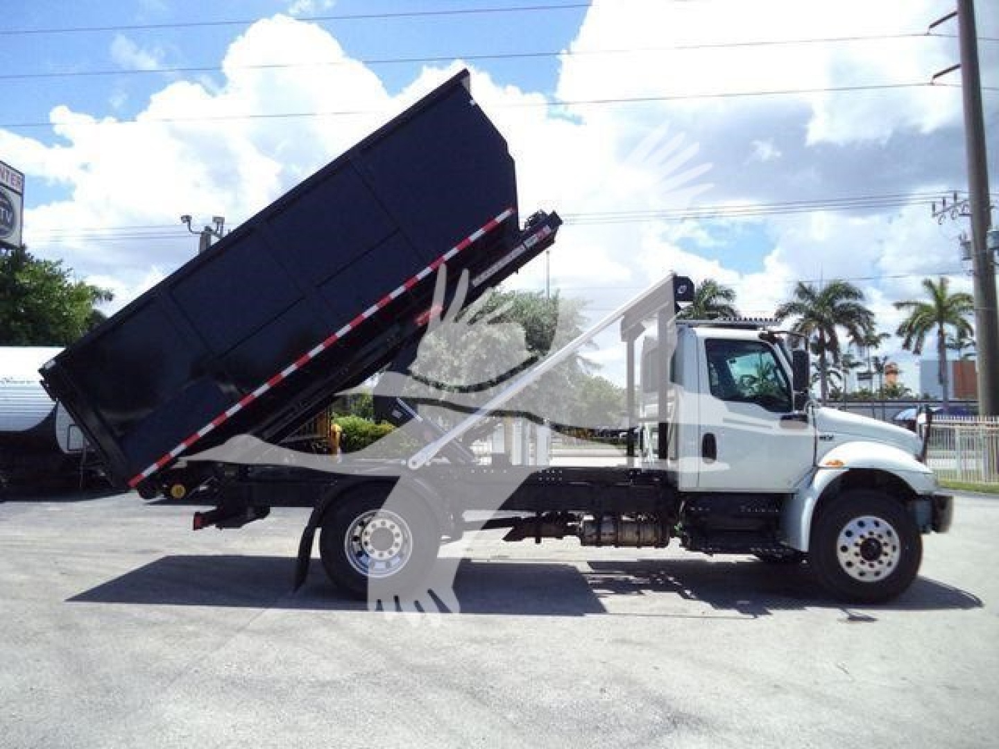 Dump truck with raised bed in service view showing cab and hydraulic dump mechanism.