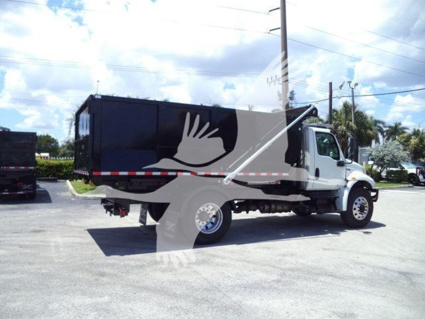 2020 International MV roll-off truck side view showing black dump body and white cab with red/white reflective stripe.