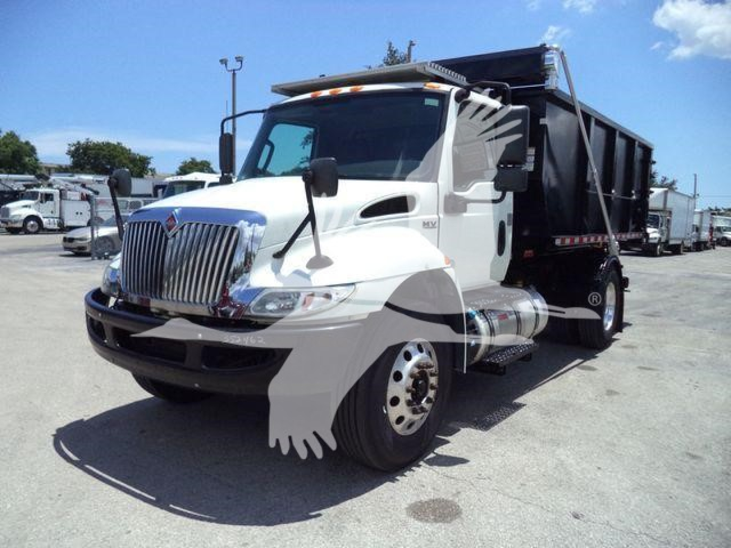 Truck cab of a white 2020 International MV roll-off with a black dump bed, showing front grille, side mirrors, and dual rear wheels.